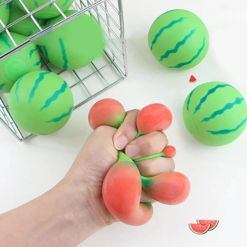 Hand holding a watermelon-themed stress ball with more balls and a basket in the background.