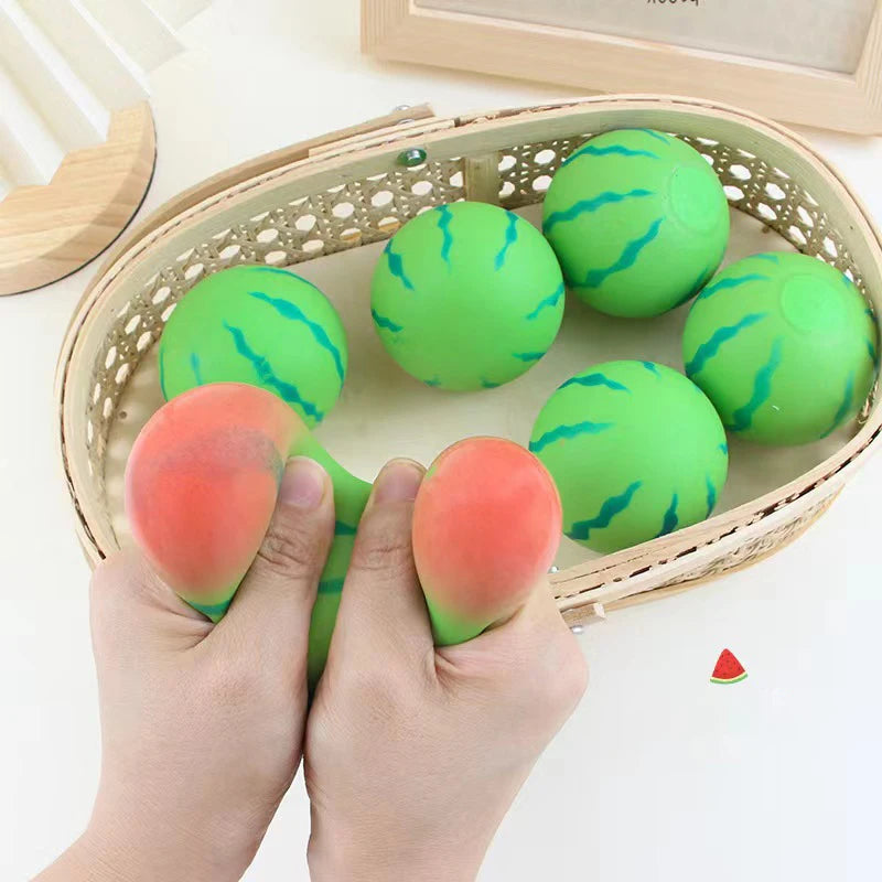 Green watermelon-themed stress balls in a basket with a hand squeezing a red stress ball.