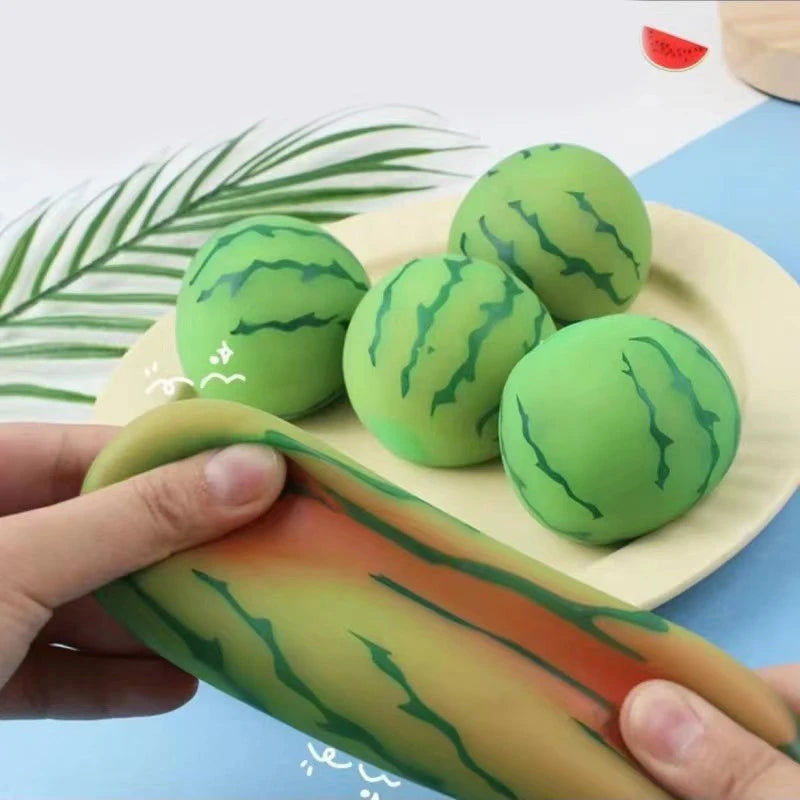Green watermelon-shaped stress balls on a plate with a hand stretching a colorful strip.
