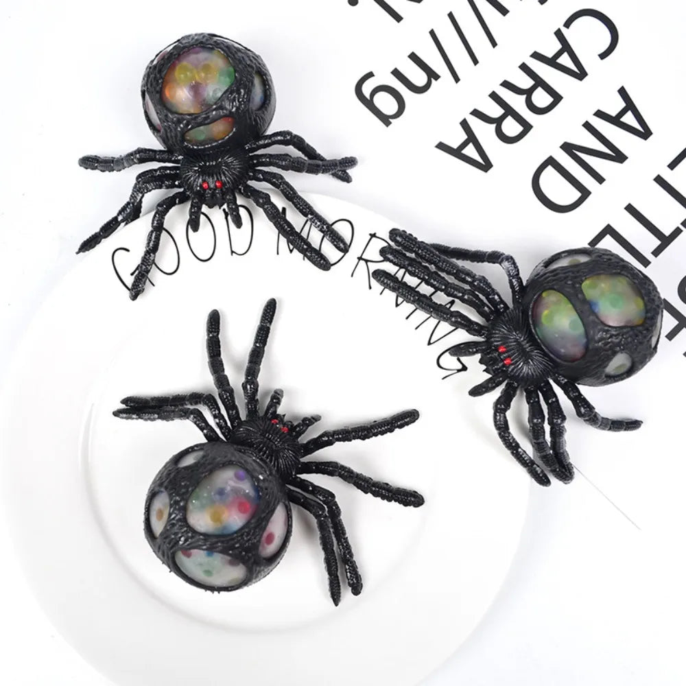 Three black toy spiders with colorful centers on a white background.