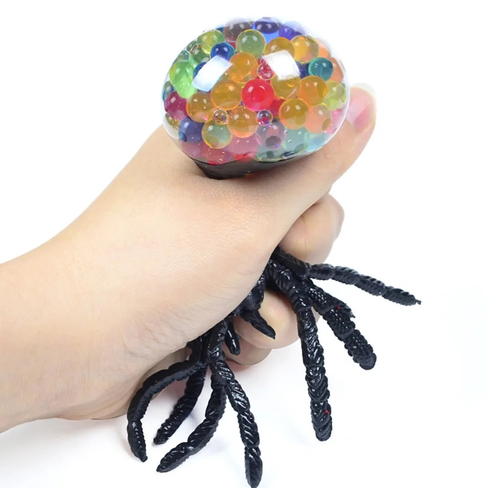 Hand holding a colorful stress ball with black spider legs on a white background