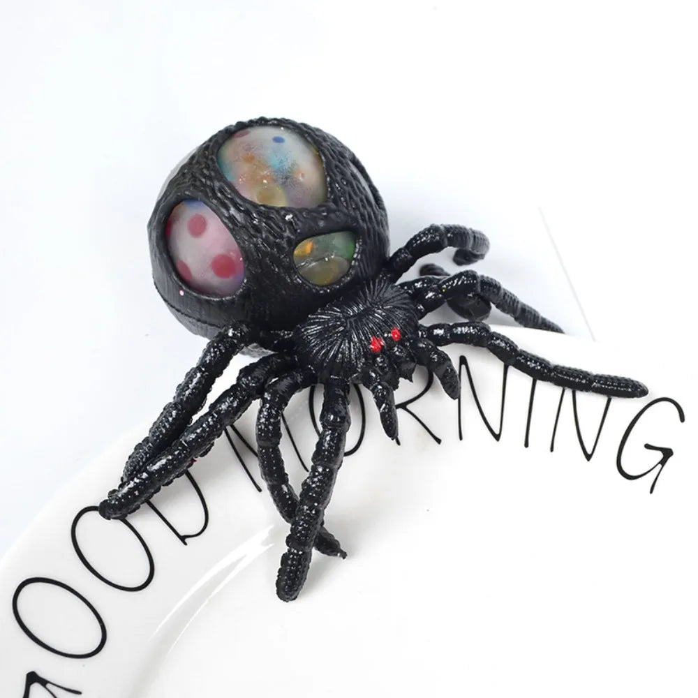 Black spider toy with colorful eyes on a white background
